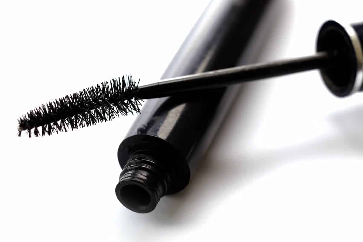 zwarte tube mascara en toverstok op een witte achtergrond