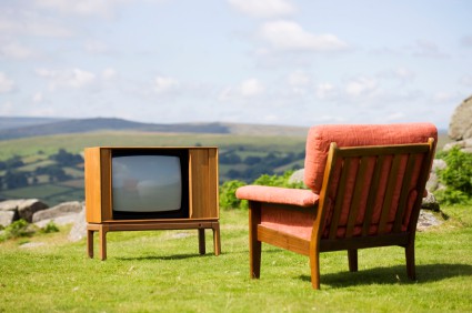 Een rode bankstoel tegenover een televisie op een bergachtergrond