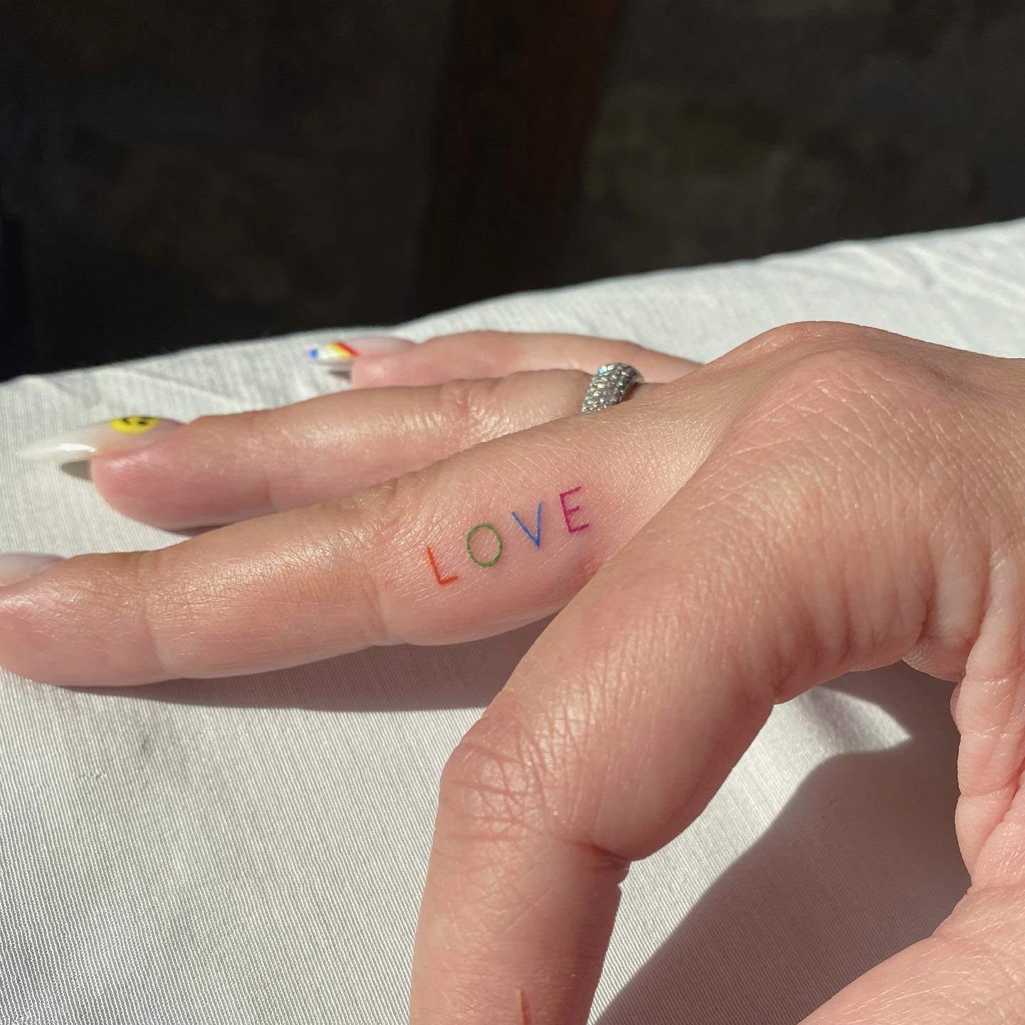 Kleurrijke Liefde Woord Tattoo op middelvinger