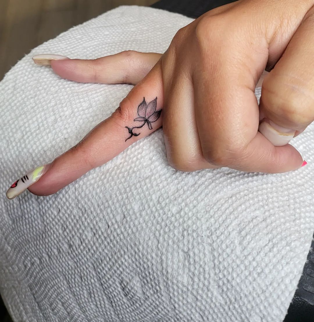 Kleine zwarte lotus tattoo binnen ringvinger