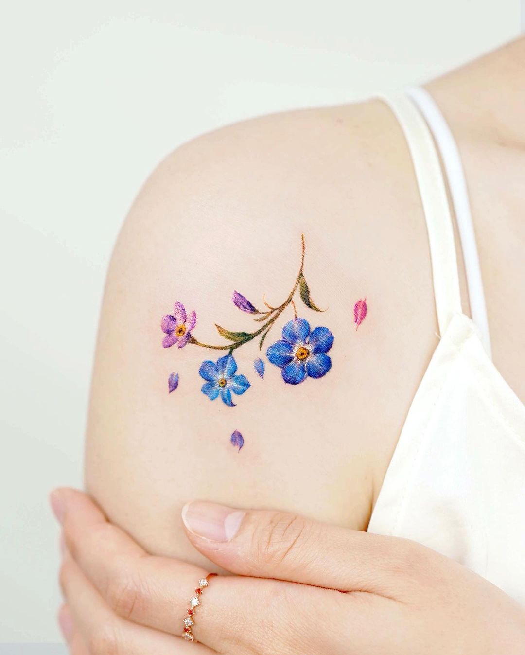 Blauw en paars Vergeet me niet tattoo op schouder