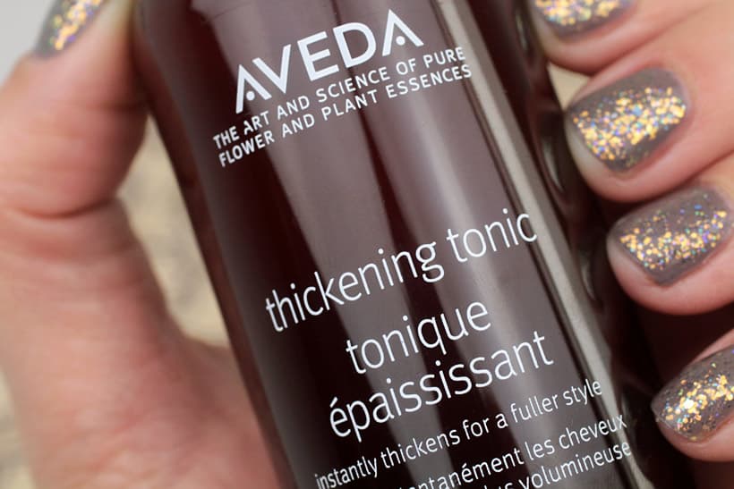 Aveda Thickening Tonic Spray voor voller haar in gemanicuurde hand