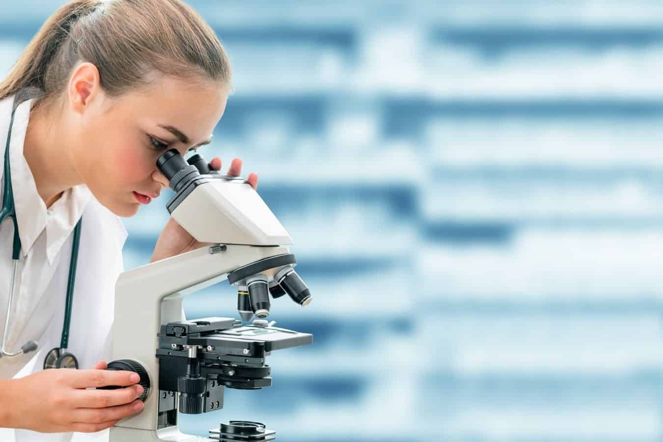 vrouw die in een microscoop kijkt