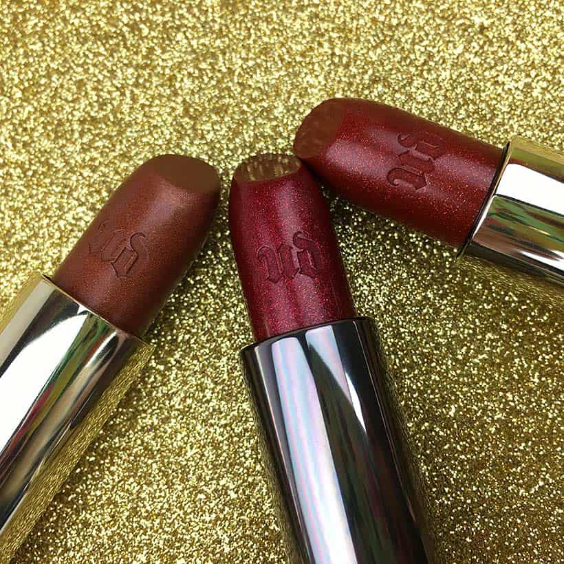 Urban Decay lippenstift op gouden glitterachtergrond in Scorched, Singe en Heat